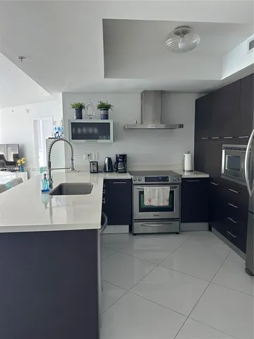 a kitchen with kitchen island granite countertop a sink stove and cabinets
