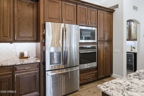 a kitchen with granite countertop a stove a sink dishwasher a refrigerator and a oven with wooden floor