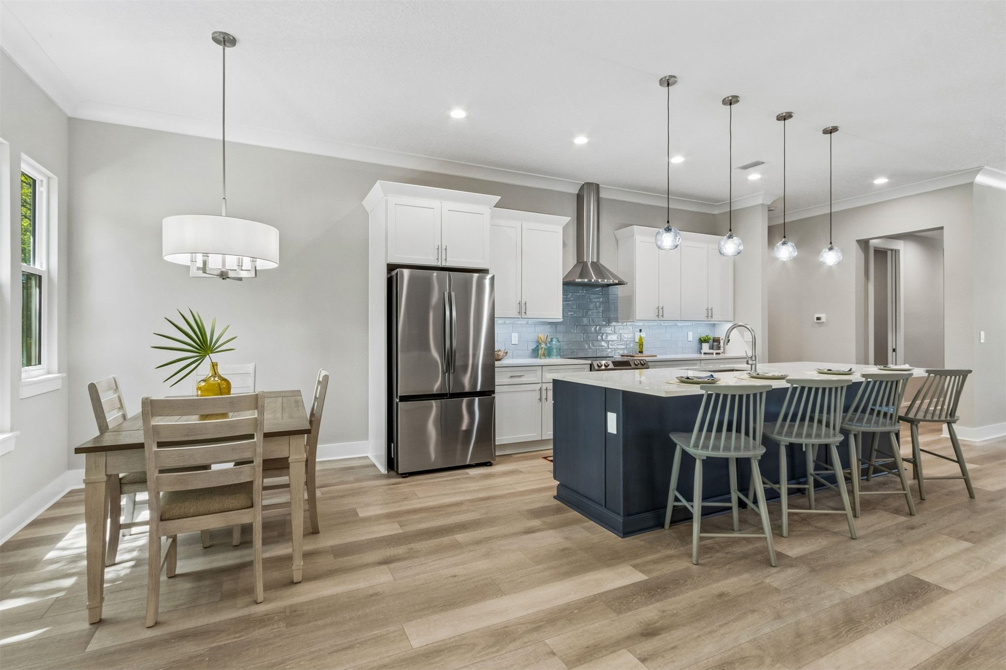 96050 Captains Pointe Road Yulee, FL 32097 - Photo 11 of 36 a kitchen with stainless steel appliances kitchen island granite countertop a table chairs and a wooden floor