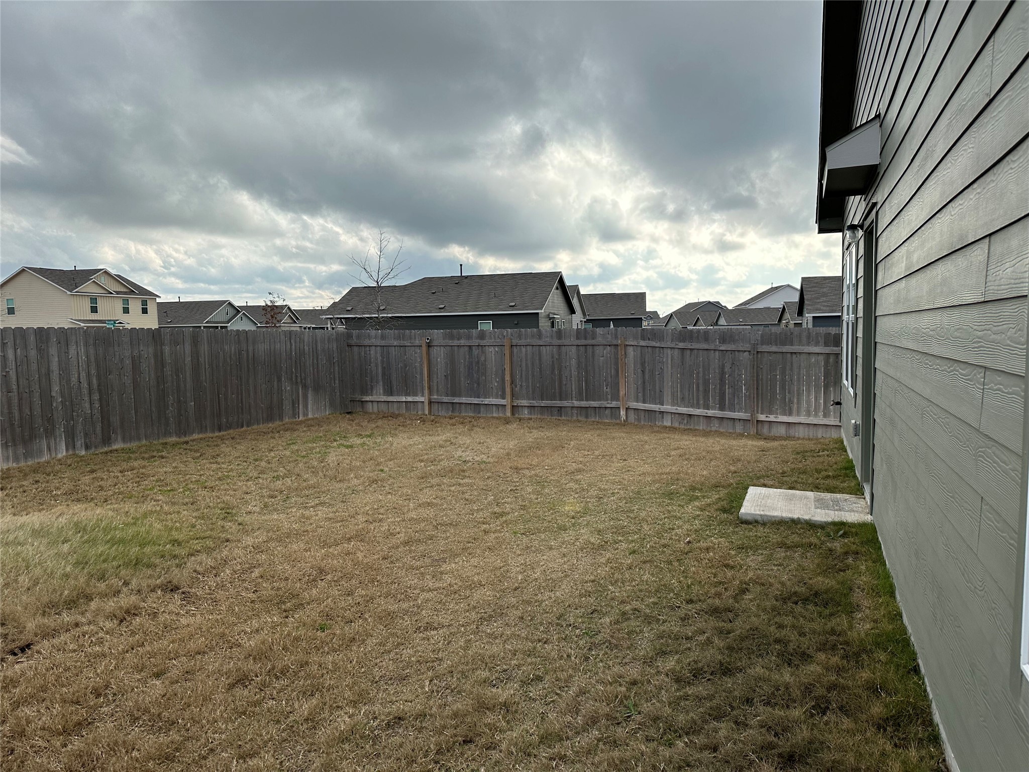 13501 Mussel Run Elgin, TX 78621 - Photo 18 of 28 Fenced backyard with wood privacy fencing, a concrete pad, and siding exterior