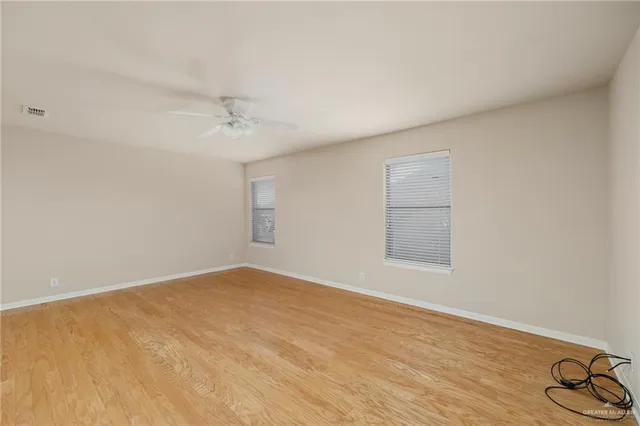 an empty room with windows and fan