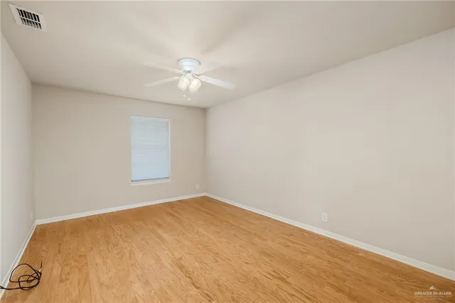 an empty room with a window and ceiling fan