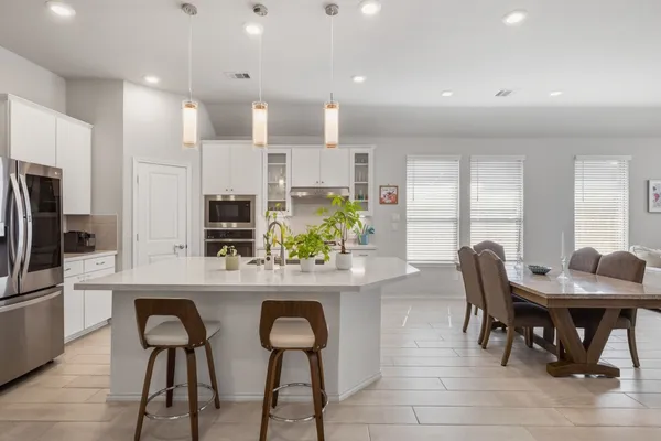 a kitchen with stainless steel appliances granite countertop a table chairs refrigerator and sink