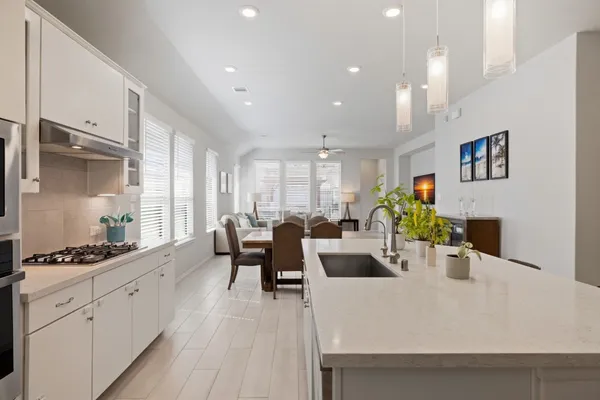 a large white kitchen with stainless steel appliances a stove a sink a dining table and chairs