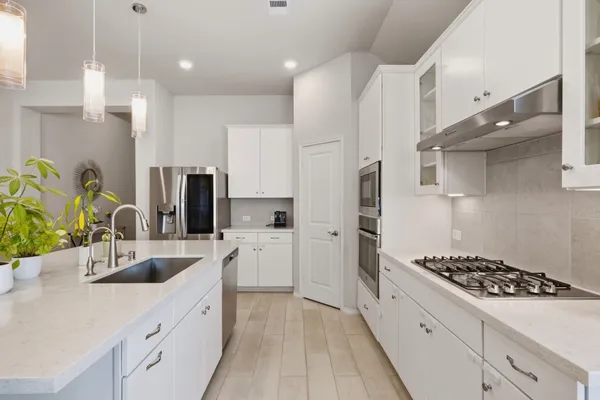 a kitchen with stainless steel appliances kitchen island wooden cabinets a sink a stove a refrigerator and a counter