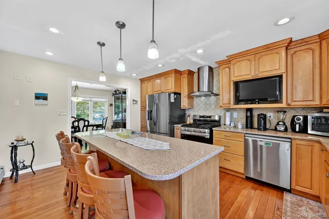 a kitchen with granite countertop stainless steel appliances a center island a stove a refrigerator cabinets dining table and chairs