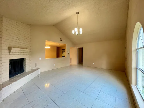 an empty room with a fireplace and chandelier