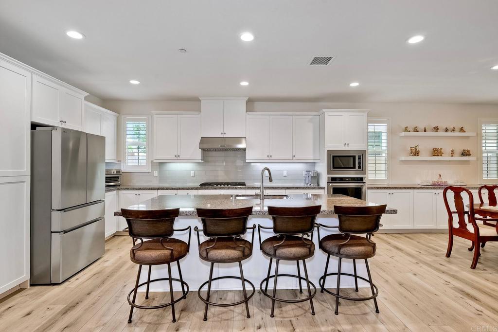 665 Gemstone Drive San Marcos, CA 92078 - Photo 7 of 49 a kitchen with stainless steel appliances granite countertop a table chairs sink refrigerator and cabinets