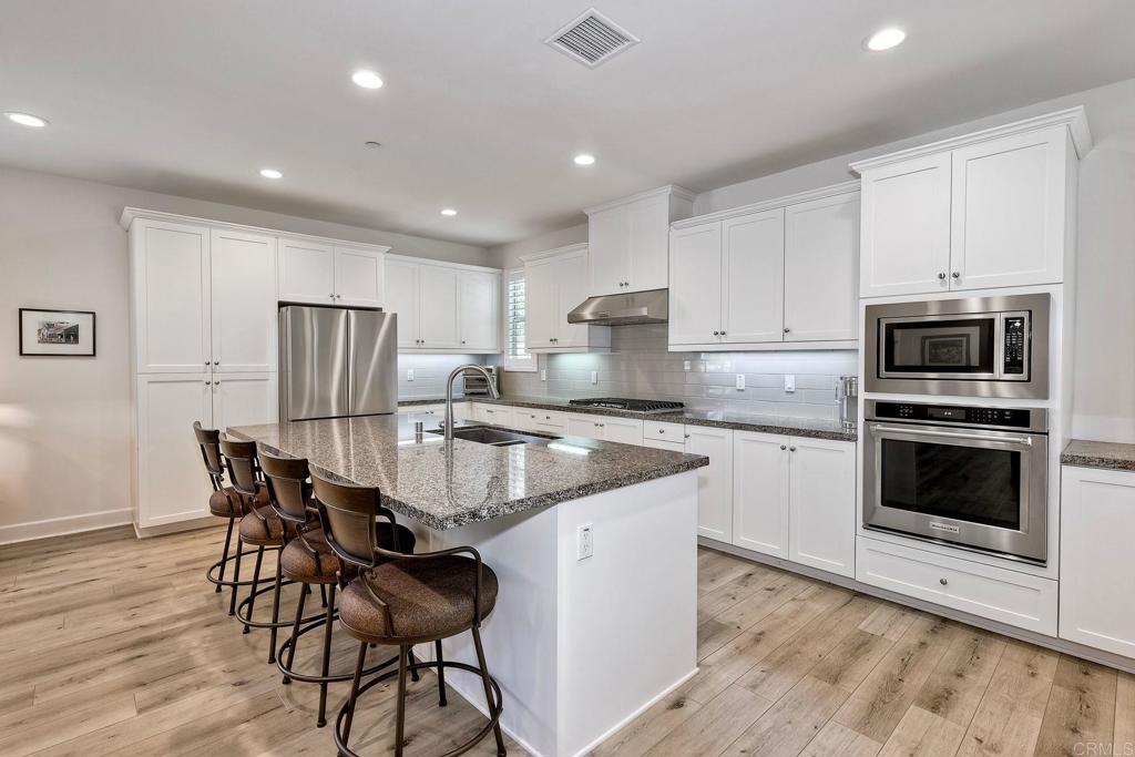 665 Gemstone Drive San Marcos, CA 92078 - Photo 8 of 49 a kitchen with granite countertop white cabinets and stainless steel appliances
