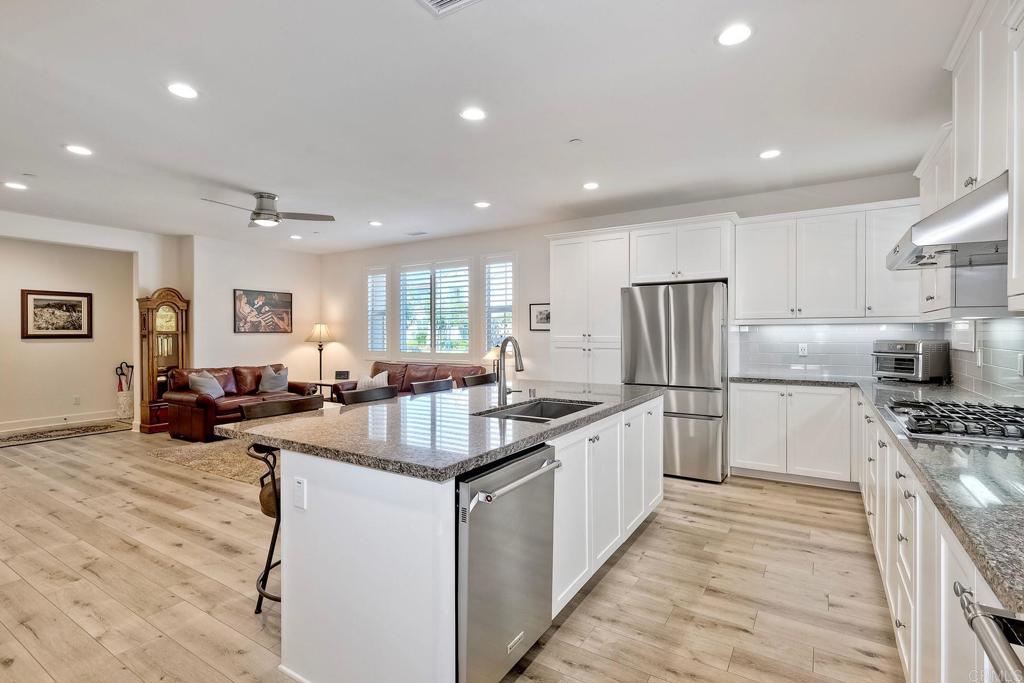 665 Gemstone Drive San Marcos, CA 92078 - Photo 9 of 49 a kitchen with stainless steel appliances granite countertop a refrigerator oven a sink dishwasher and white cabinets with wooden floor