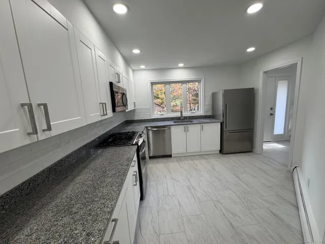 a large kitchen with stainless steel appliances granite countertop a refrigerator and a sink
