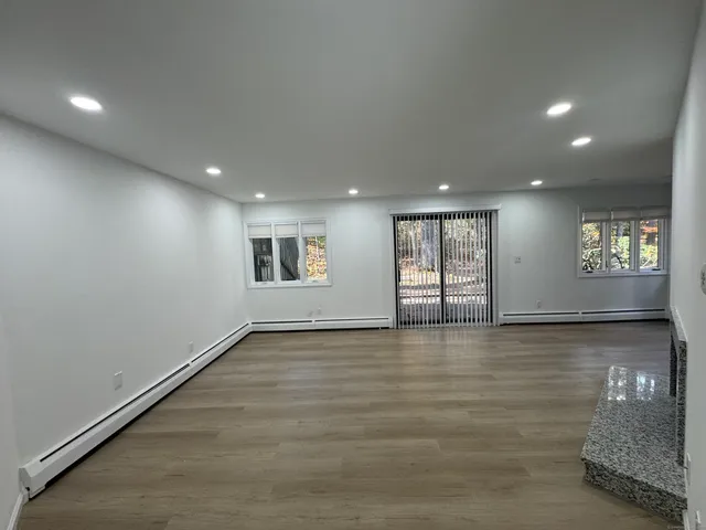 a view of an empty room with window and wooden floor