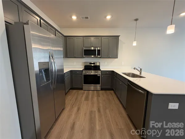 a kitchen with kitchen island a counter top space a sink a refrigerator and a stove