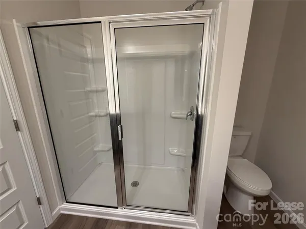 a bathroom with a glass door shower a toilet and a sink