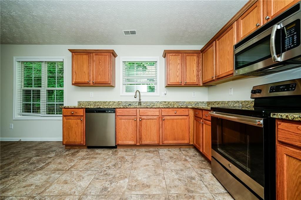 4468 Abram Way Conley, GA 30288 - Photo 23 of 23 a kitchen with stainless steel appliances granite countertop a stove a sink and a microwave