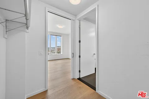 a view of an empty room with wooden floor and a bathroom