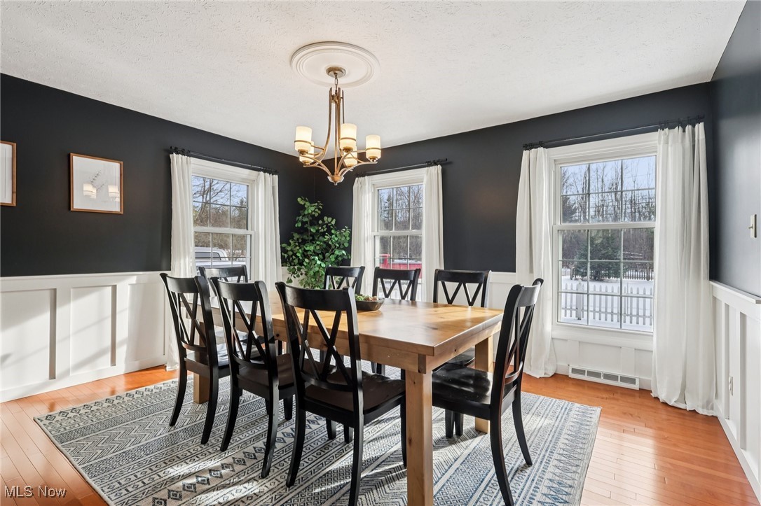445 Center Road Hinckley, OH 44233 - Photo 6 of 50 Dining room with a wainscoted wall, a decorative wall, light wood finished floors, a textured ceiling, and a chandelier