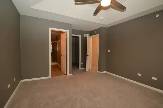 an empty room with closet and a chandelier fan