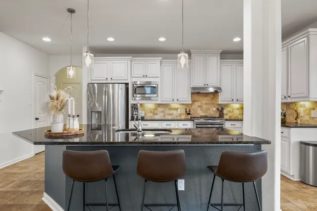 a kitchen with refrigerator and chairs