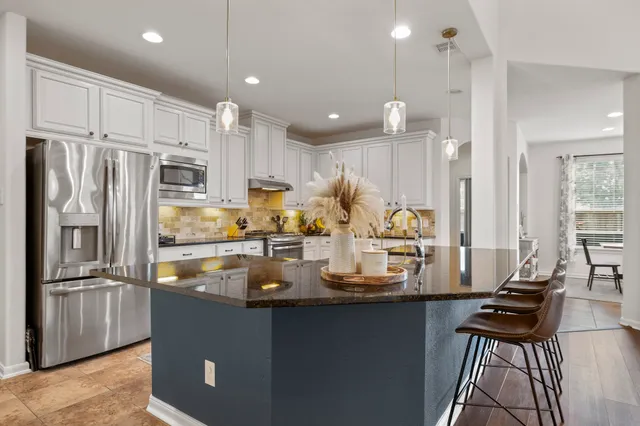 a kitchen with stainless steel appliances granite countertop a sink refrigerator and cabinets