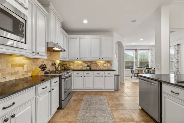 a kitchen with granite countertop white cabinets and stainless steel appliances