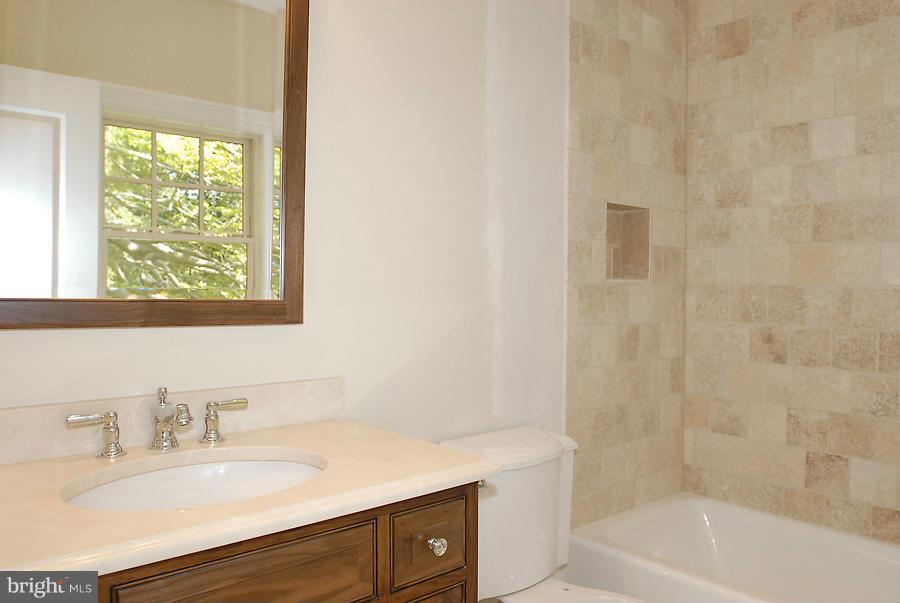 8539 Howell Road Bethesda, MD 20817 - Photo 17 of 22 a bathroom with a tub sink vanity and a mirror