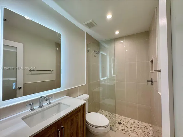 a bathroom with a sink a toilet a shower and a mirror