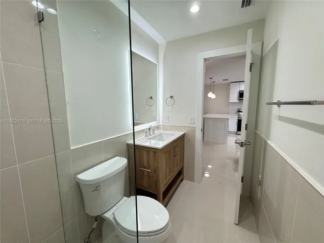 a bathroom with a sink a toilet a mirror and shower