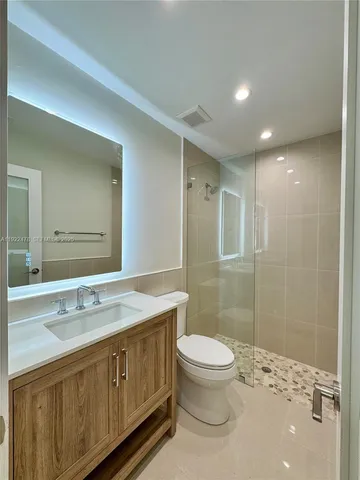 a spacious bathroom with a sink a toilet a shower and a mirror