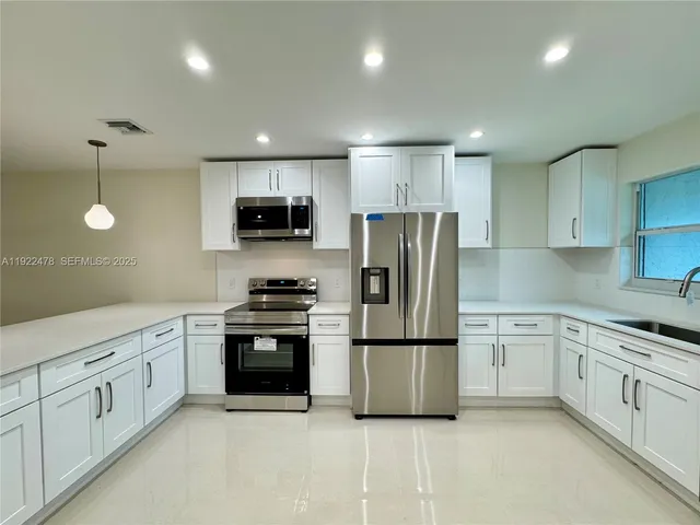 a kitchen with white cabinets and stainless steel appliances