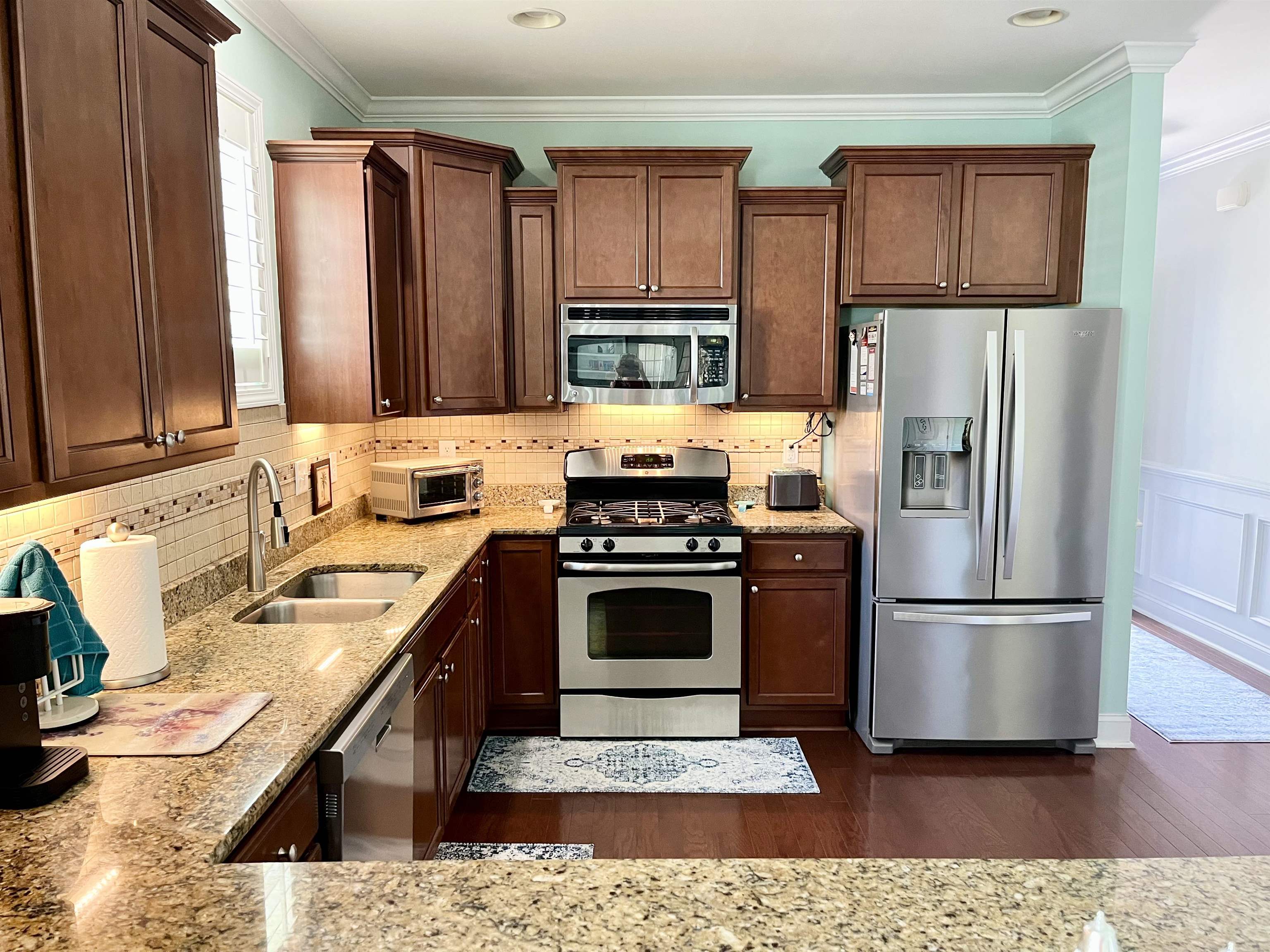 151 Coral Beach Circle Myrtle Beach, SC 29575 - Photo 11 of 40 Kitchen featuring appliances with stainless steel finishes, light stone counters, dark wood finished floors, ornamental molding, and tasteful backsplash