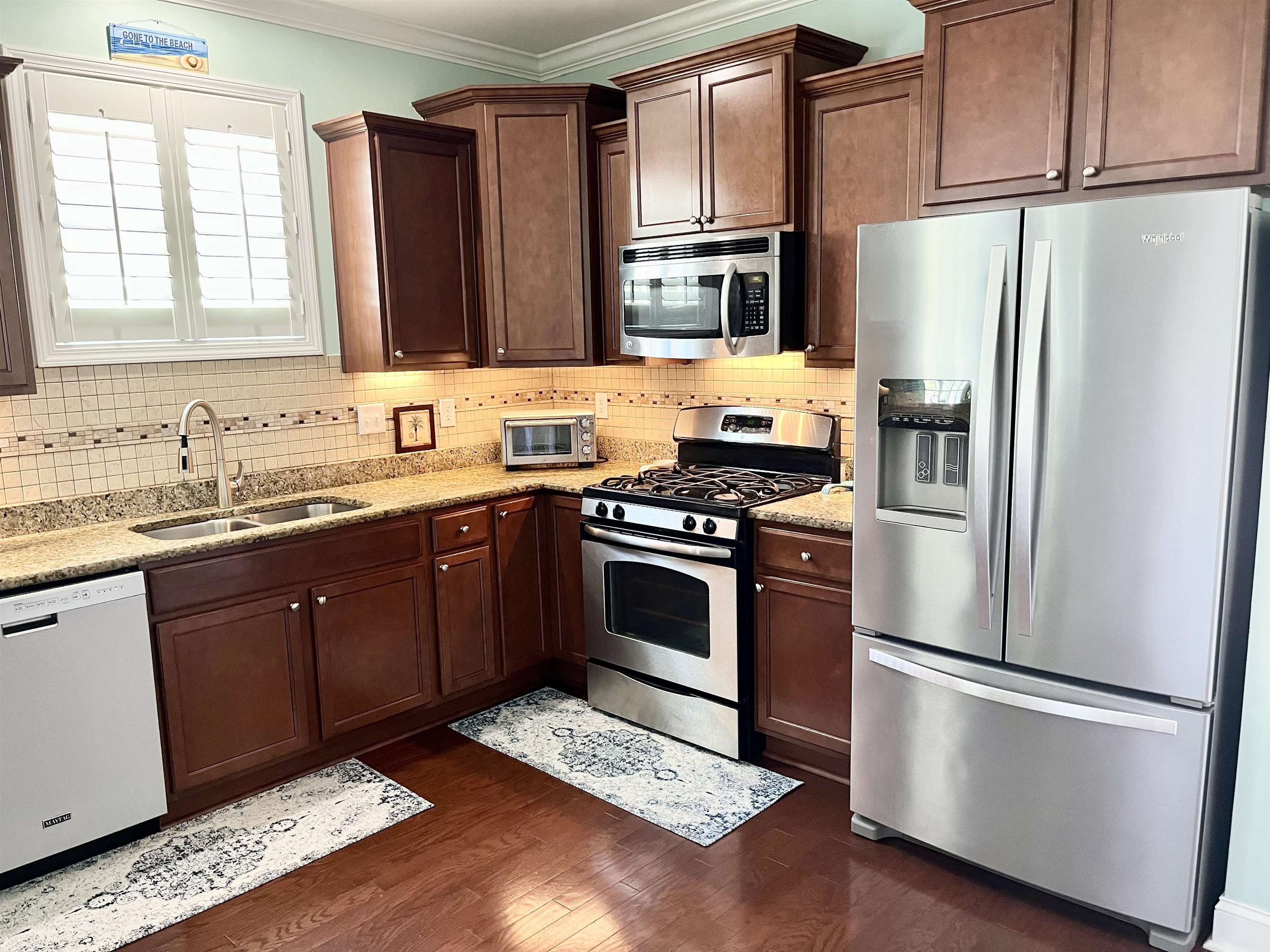 151 Coral Beach Circle Myrtle Beach, SC 29575 - Photo 9 of 40 Kitchen featuring appliances with stainless steel finishes, light stone countertops, dark brown cabinets, dark wood-type flooring, and ornamental molding