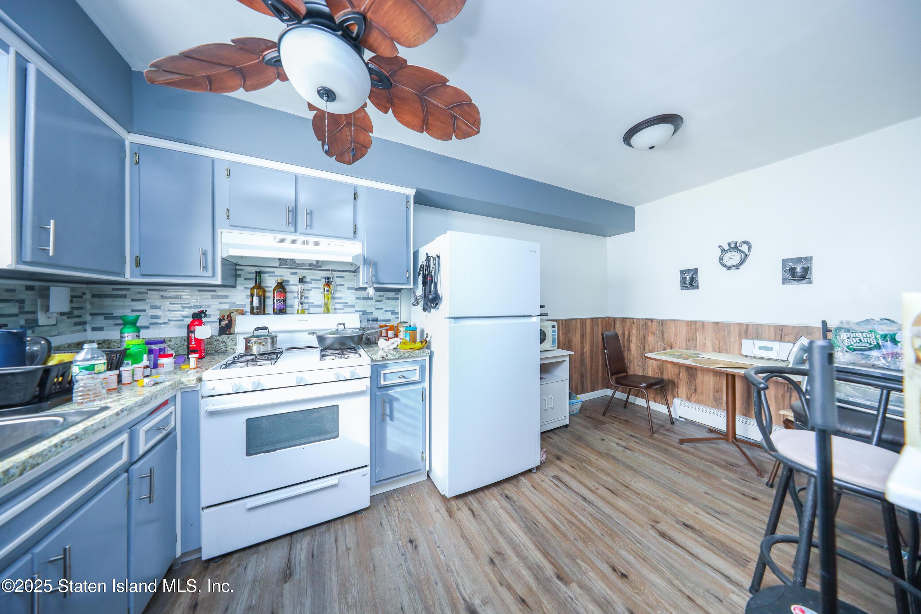 268 Ada Drive Staten Island, NY 10314 - Photo 19 of 27 a kitchen with stainless steel appliances a stove a refrigerator and white cabinets with wooden floors