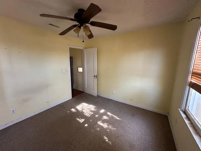 an empty room with windows and fan