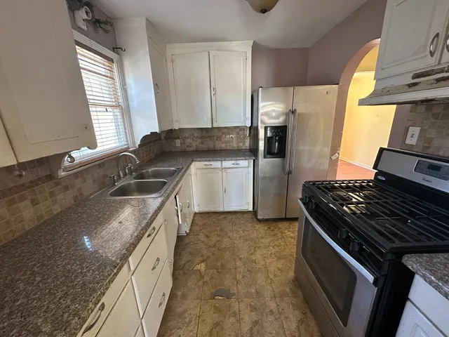 a kitchen with granite countertop a sink stove and refrigerator