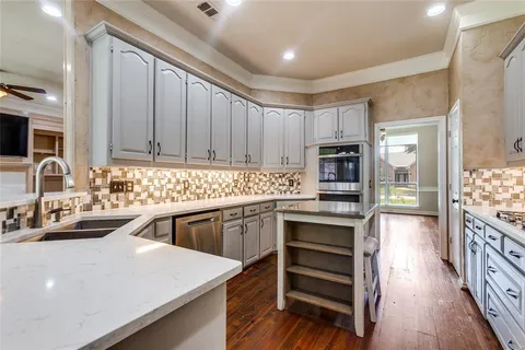 a kitchen with kitchen island granite countertop a sink stove and cabinets
