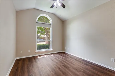 an empty room with a window and wooden floor