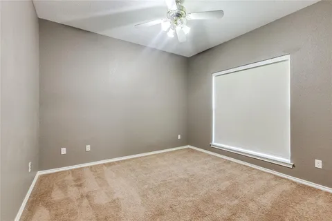 an empty room with a chandelier fan and windows