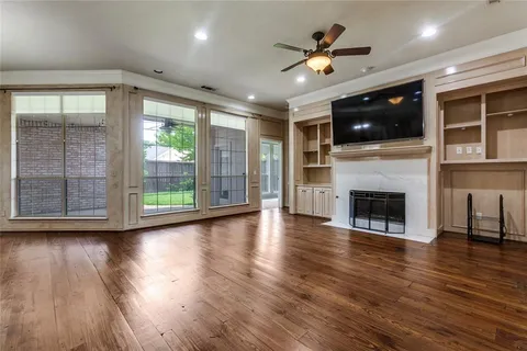 a view of an empty room with wooden floor a fireplace and a window