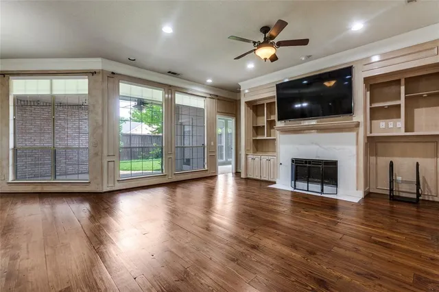 a view of an empty room with wooden floor a fireplace and a window