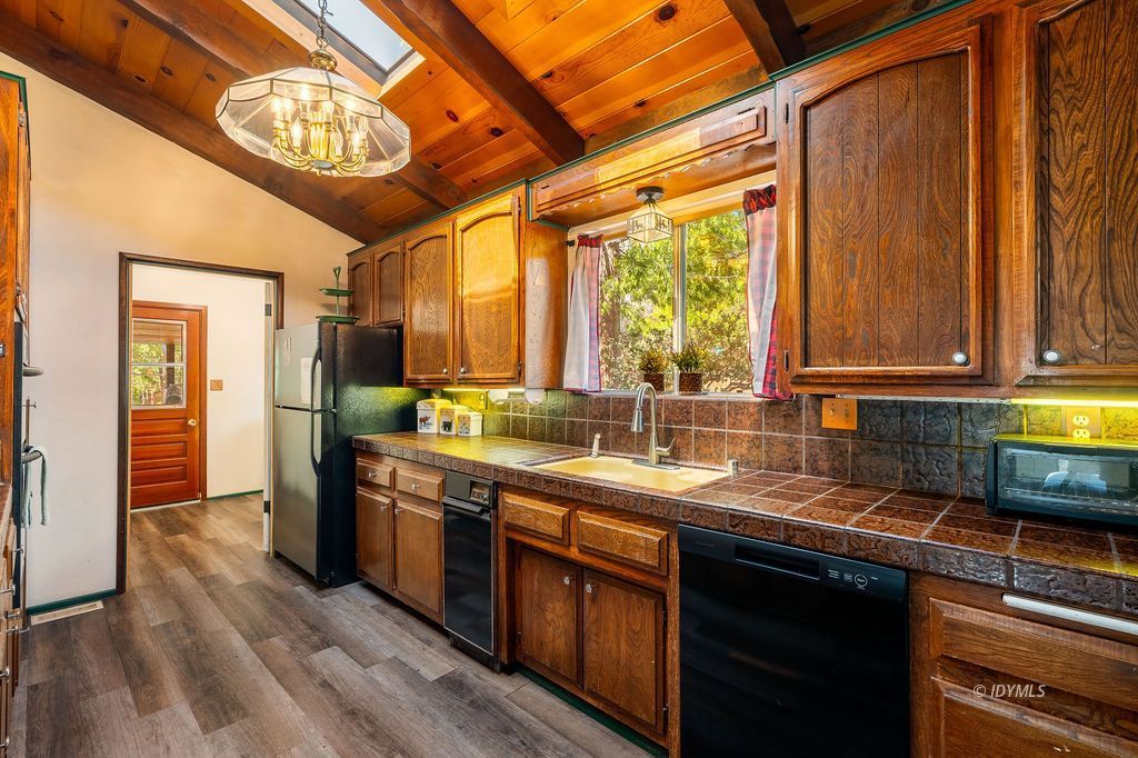 25580 Fir Street Idyllwild, CA 92549 - Photo 16 of 48 a kitchen with stainless steel appliances granite countertop a sink a stove cabinets counter space and a window