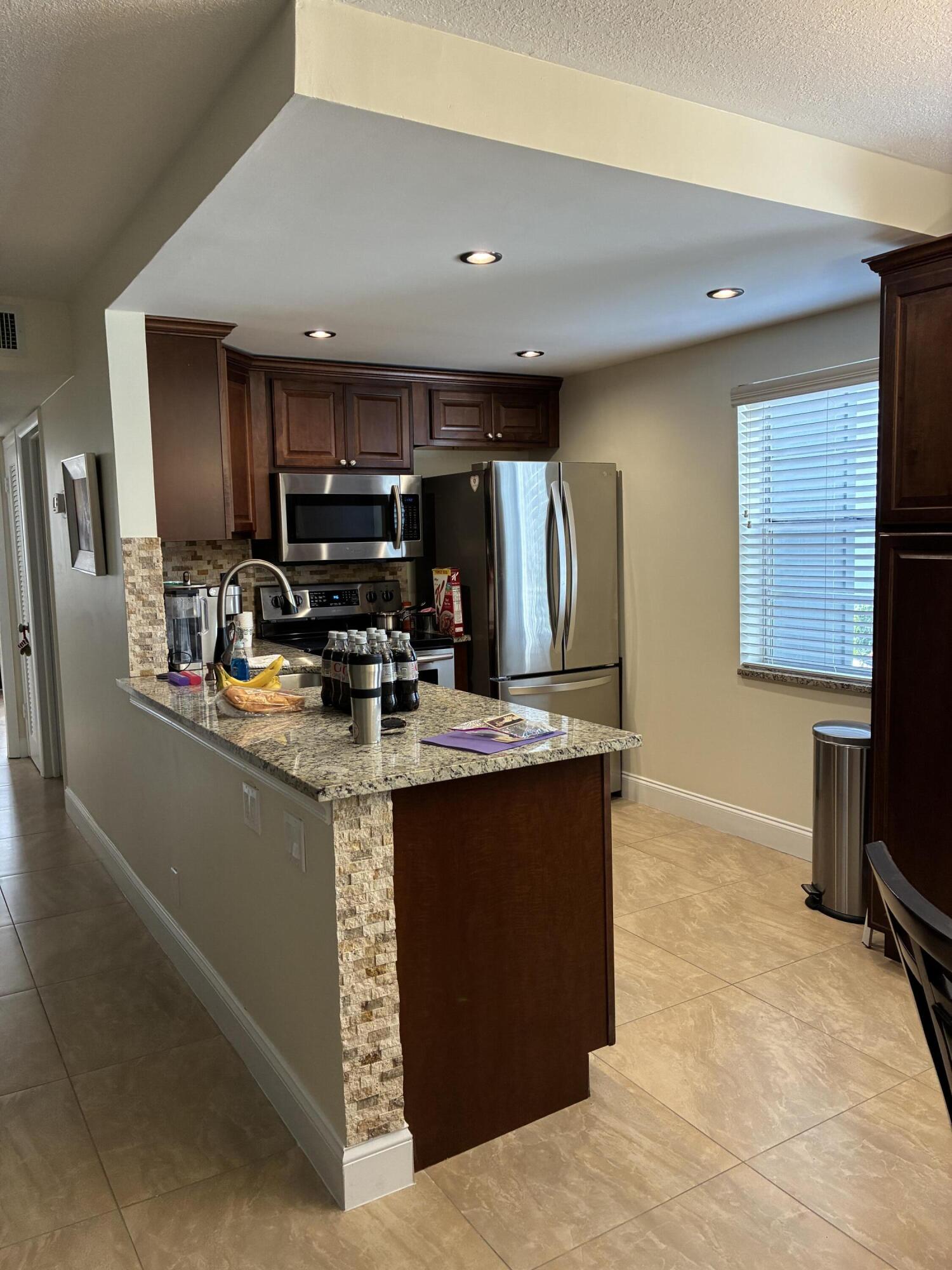 355 Normandy Lane Delray Beach, FL 33484 - Photo 4 of 33 a kitchen with kitchen island stainless steel appliances a sink stove and refrigerator
