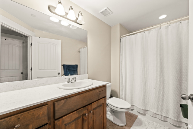 1145 North Christley Lane, Unit 48 Elk Ridge, UT 84651 - Photo 23 of 38 Spacious bathroom featuring an oval undermount sink set into a light-toned countertop, a wood-finish vanity with cabinet storage, a wide mirror, and an overhead light bar
