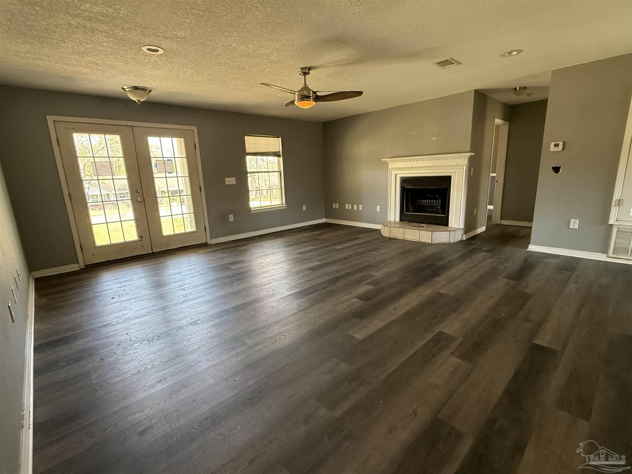 1009 Rachel Circle Cantonment, FL 32533 - Photo 2 of 11 an empty room with wooden floor fireplace and windows