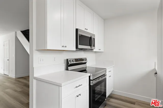 a utility room with stainless steel appliances white cabinets and a stove top oven