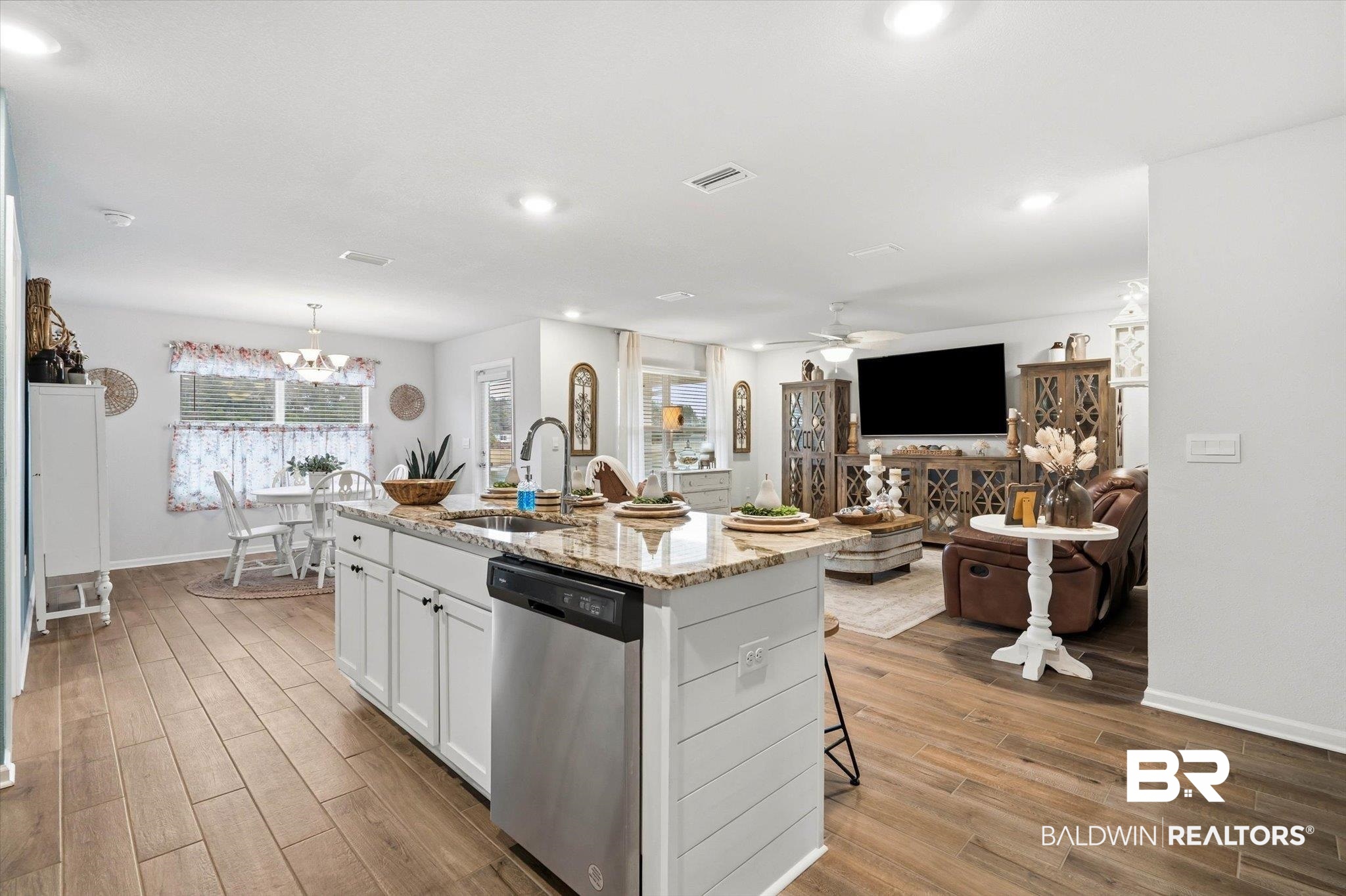 17041 Muse Street Loxley, AL 36551 - Photo 43 of 44 Kitchen featuring white cabinets, stainless steel dishwasher, light stone countertops, open floor plan, and a center island with sink