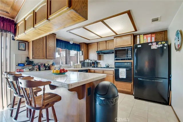 a kitchen with stainless steel appliances granite countertop a refrigerator a stove a sink a dining table and chairs with wooden floor