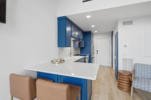 a kitchen with stainless steel appliances a sink a microwave a refrigerator and wooden cabinets