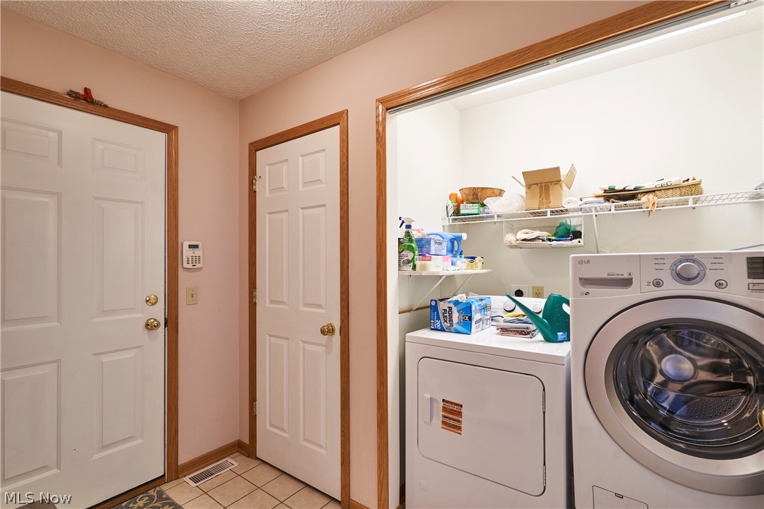 1963 Haines Road Madison, OH 44057 - Photo 27 of 34 Dedicated laundry area featuring a white LG front-load washer and dryer, convenient wire shelving, and tiled flooring