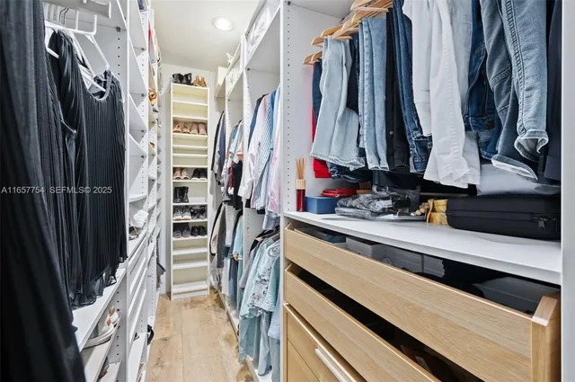 a view of walk in closet with clothes and shoes